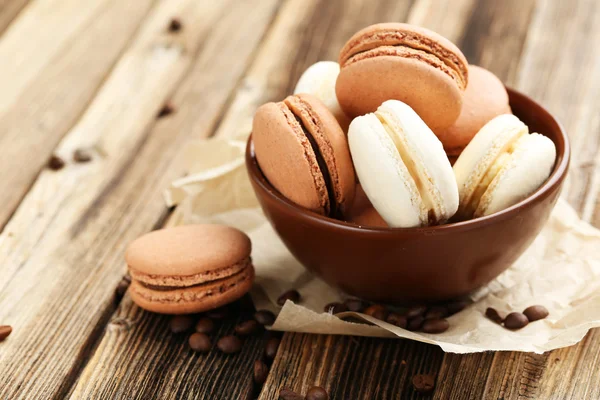 Coffee macarons with coffee beans on brown wooden background — Stock Photo, Image