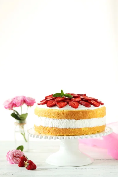 Zoete cake met aardbeien op de plaat op witte houten achtergrond — Stockfoto