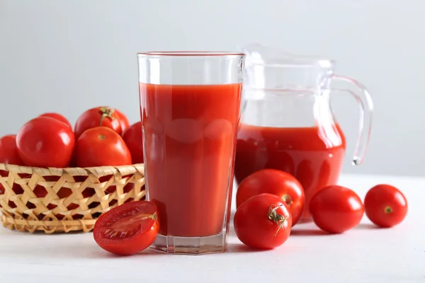 Tomates vermelhos frescos em cesta e suco de tomate — Fotografia de Stock