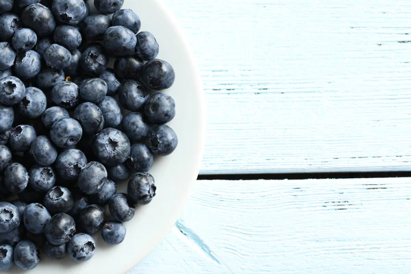 Bleuets dans une assiette sur fond en bois — Photo