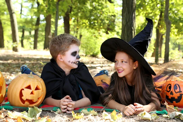 Hermosa chica bruja y niño pequeño con calabaza en el parque, o —  Fotos de Stock