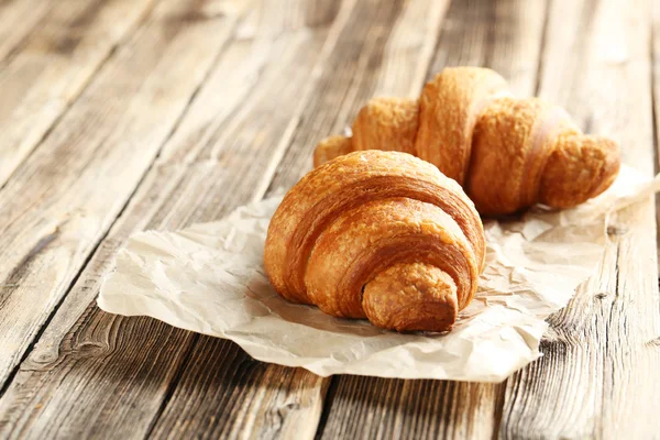 Chutné croissanty na dřevěném pozadí — Stock fotografie