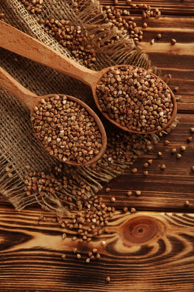 Buckwheat seeds in wooden spoons — Stock Photo, Image