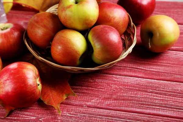 Ripe apples in basket with autumn leaves — Stock Photo, Image