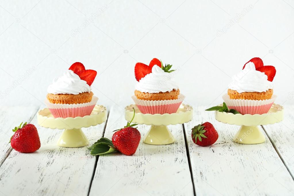 Tasty cupcakes with strawberries on cake stand