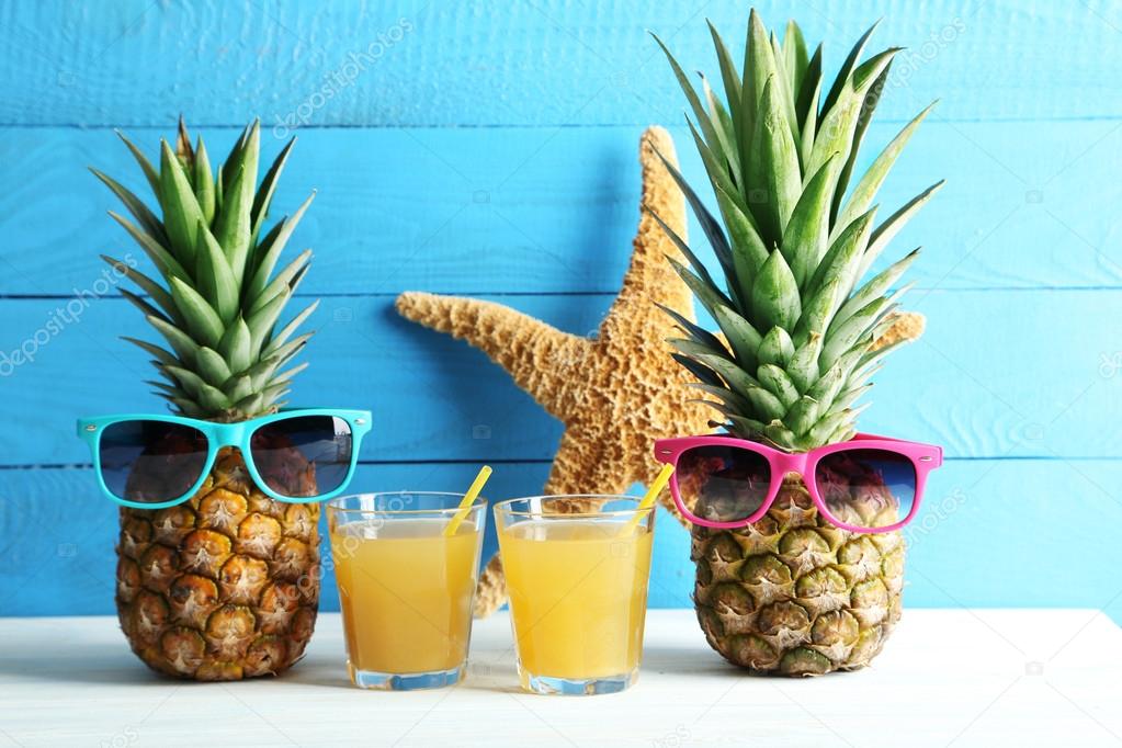 Ripe pineapples with glasses of juice