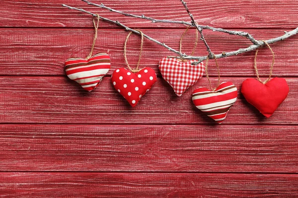 Love hearts hanging on a tree branch on a red wooden background — Stock Photo, Image