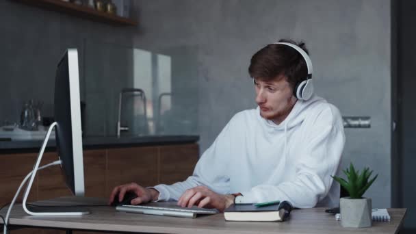 Jongeman die thuis online werkt, terwijl hij naar muziek luistert. Quarantaineconcept voor zelfisolatie — Stockvideo