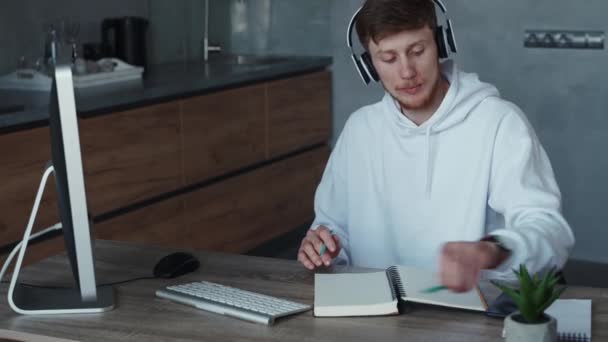 Jongeman die thuis online werkt, terwijl hij naar muziek luistert. Quarantaineconcept voor zelfisolatie — Stockvideo