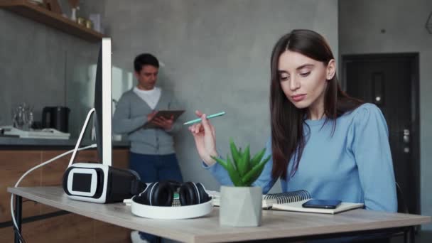 Meslektaşı arka planda tabletle dururken bilgisayarda yazan genç bir kadın. Takım çalışması konsepti — Stok video