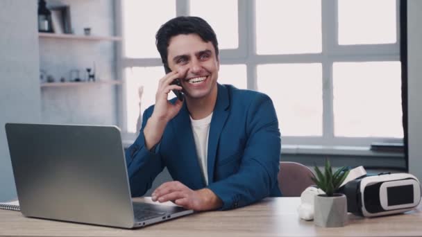 L'uomo ha una telefonata in ufficio con grandi finestre panoramiche utilizzando laptop e auricolari vr — Video Stock