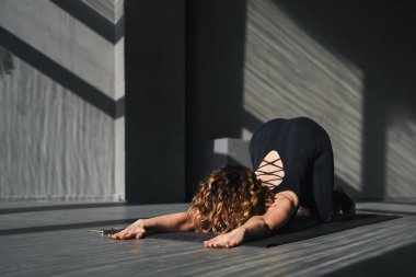 Güneşli bir günde, arka planda yoga yapan genç bir kadın.