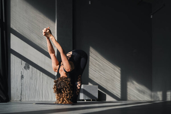 Young woman practicing yoga poses in an urban background on sunny day