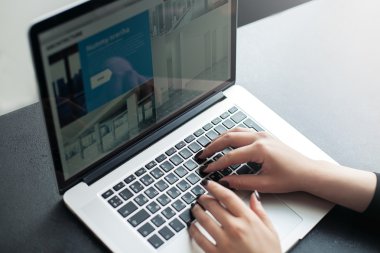 Laptop ile kadının ellerini kullanarak dizüstü bilgisayar ve akıllı telefon, kadın teknolojisini kullanarak onun işyerinde çalışan bir genç kadın kadeh ışık parlaması