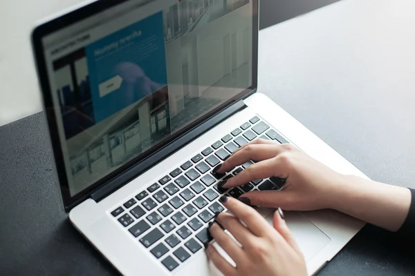 Shot of a young woman working with laptop, womans hands using notebook computer and smart phone, woman at her workplace using technology, flare light — Stock Photo, Image