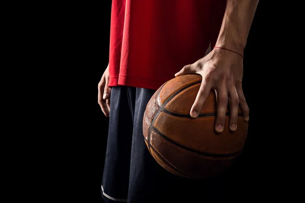 Jogador detém uma bola de basquete em uma mão isolada em preto — Fotografia de Stock