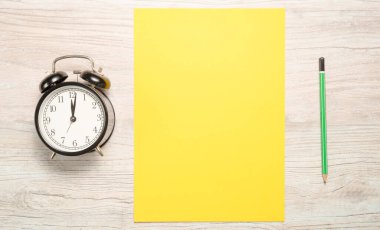 Yeni yıl için metin yazmak için sarı boş kart veya kararları tahta bir arka planda bir saat ve bir kalem ile birlikte
