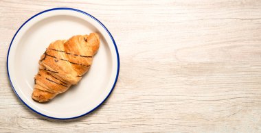 Mutfak masasında beyaz bir tabakta kruvasan ve metin için yer var.