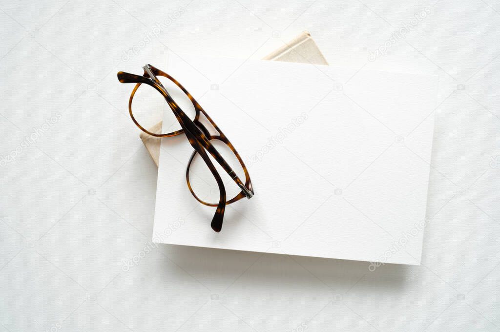 blank white invitation template, rectangle, art canvas texture, soft shadows, brown glasses, white background, canvas texture, photo taken from above