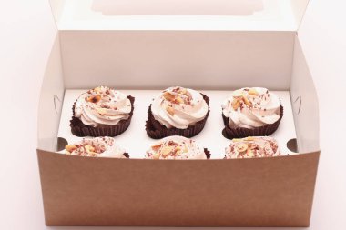 Beyaz arka planda açık bir hediye kutusunda kremalı lezzetli çikolatalı kekler.