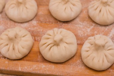 Tahta üzerinde un bulunan yarı bitmiş Gürcü yemeği khinkali.