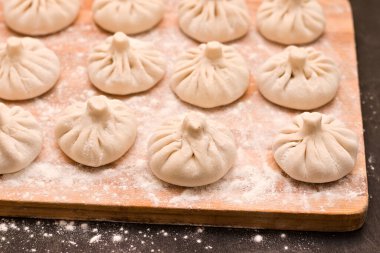 Yanında merdane olan ince sıra pişmemiş Gürcü Khinkali.