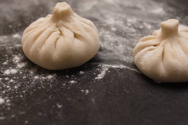 Siyah bir masaya un serpiştirilmiş Gürcü hinkalisi. Yan görünüm