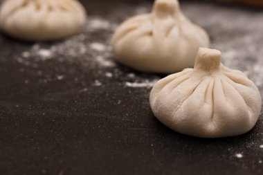 Masaya un serpiştirilmiş üç çiğ Gürcü khinkali. Yan görünüm