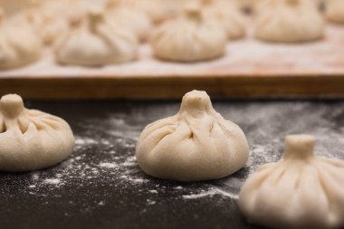Ahşap tahta kenarlı bir görünümde ham khinkali 'nin odaklanmış görüntüsü. Ahşap tahta kenarlı bir görünümde ham khinkali' nin odaklanmış görüntüsü.