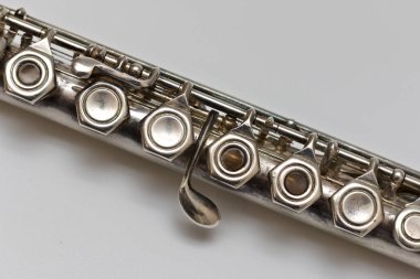 Parlak gümüş bir flüt beyaz bir çarşafın üzerinde çapraz olarak yatar.