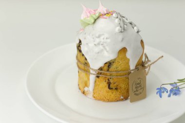 Bahar çiçeklerinin arka planında sicimle bağlı beyaz bir tabakta paskalya pastası.