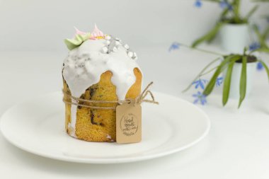 Beyaz şekerli Ortodoks Paskalya pastası ve bir tepside halatla bağlanmış şekerlemeler ve kapta bahar çiçekleri.