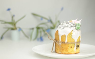 Ortodoks Paskalya pastası, beyaz bir arka planda saksıda bahar çiçekleri olan bir tabakta iple bağlanmış.