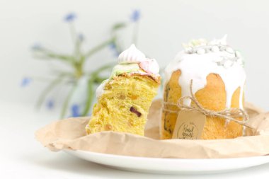 Paskalya pastasını bahar çiçeklerinin arka planında beyaz bir tabakta kes