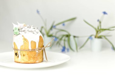 Bahar çiçeklerinin arka planında sicimle bağlı beyaz bir tabakta paskalya pastası.