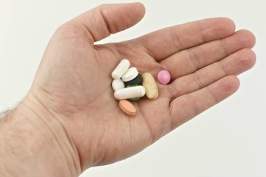 Beyaz arka planda bir adamın elinde bir avuç dolusu hap..