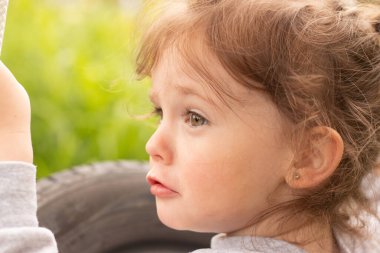 Küçük, güzel, kızıl saçlı kız siyah bir tekerleğin üzerinde, iplerle bağlı, açık havada.