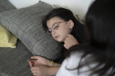 Gözlüklü üzgün kız kanepede yastığa uzanırken annem evde başını okşuyor, ilgi ve destek kavramı..