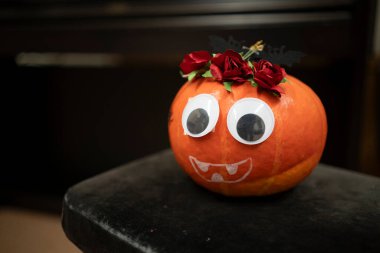 Bulanık arka planda gözleri ve ağzı olan küçük boyalı balkabağı. Şirin el yapımı Cadılar Bayramı dekorasyonu yaratıcılığı ve şenlikli sonbahar havasını simgeliyor..