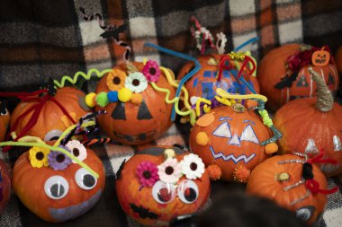 Tahta bir bankta kareli bir battaniyenin üzerinde diğerlerinin yanında duran süslü bir balkabağı. Sıcak bir sonbahar, ılık bir hayat ve neşeli bir Cadılar Bayramı havası..