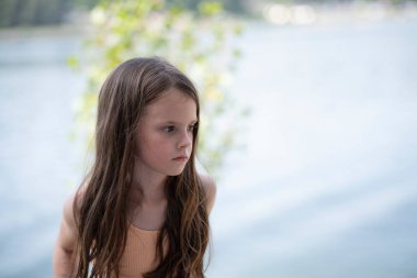 Düşünceli kız yukarı bakıyor, su yüzeyine yakın, bulanık arka plan, fotokopi alanı olan duygusal çocukluk portresi.