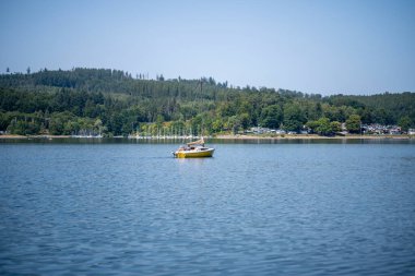 Sorpsee, NRW, Almanya. 13 Ağustos 2025. Sakin göl suyu, ulaşım ve yaz günü fotokopi alanı ile hareket eden, motorlu yelkenli.