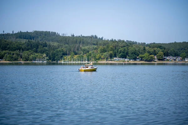 Sorpsee, NRW, Almanya. 13 Ağustos 2025. Sakin göl suyu, ulaşım ve yaz günü fotokopi alanı ile hareket eden, motorlu yelkenli.