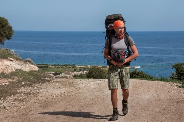 Человек с большим рюкзаком на дороге море — стоковое фото