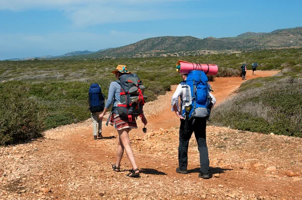 Group of tourists with large backpacks are on road sea — Stock Photo, Image