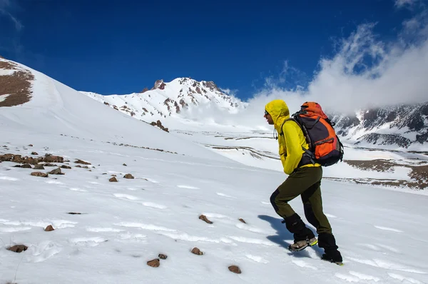 Homme grimpeur monte sur un volcan enneigé . — Photo