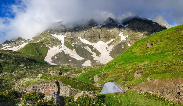 Gray tent in grass on background of mountains and rocks — Stock Photo, Image