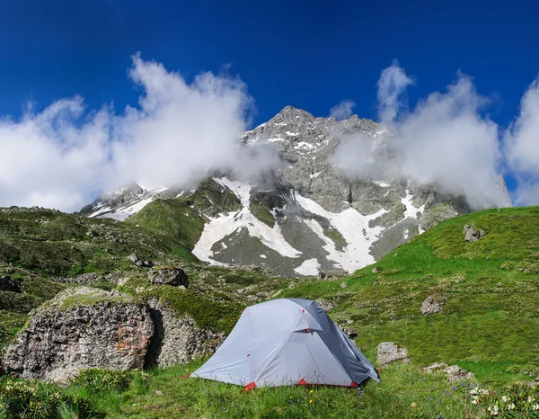 Gray tent in grass on background of mountains and rocks — Stock Photo, Image