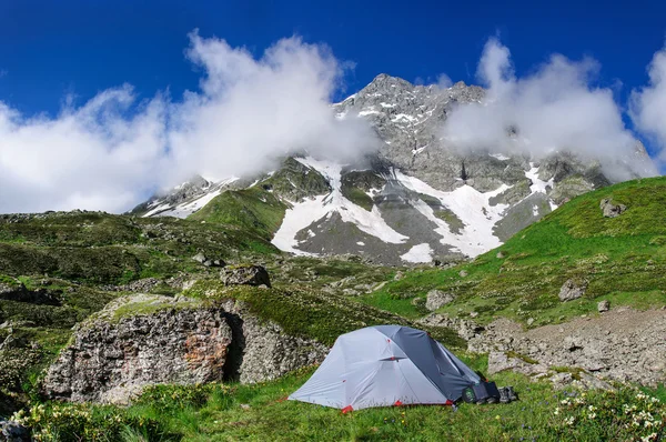 Gray tent in grass on background of mountains and rocks — Stock Photo, Image