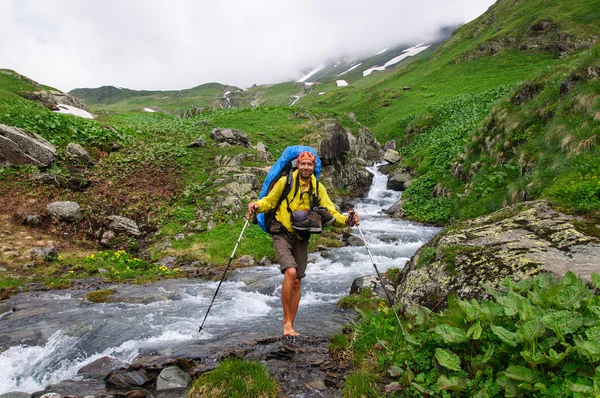 The tourist with a big backpack crossing  river ford. — Stock Photo, Image